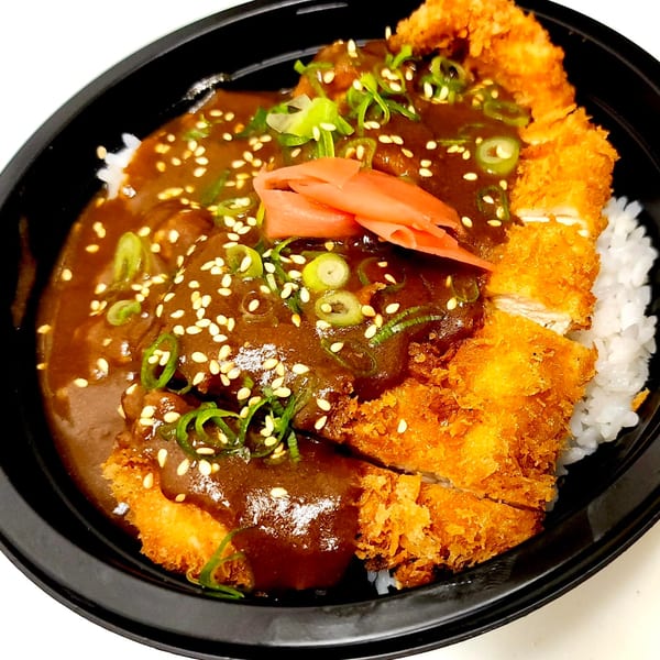 Nanabi Cafe's chicken katsu curry with rice, garnished with pickled ginger, green onions, and sesame seeds.
